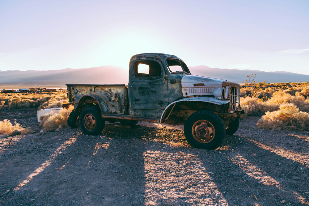 A vintage pickup truck near farming fields, on the side of the road. It's a shorter bed, so they need to measure to understand how much mulch fits in a truck bed.